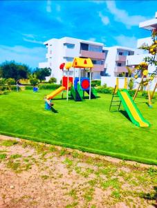 a playground with a slide in a park at Appartement standing avec piscine à ImiOuaddar in Agadir +11 photos