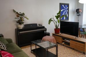 een woonkamer met een bank en een piano bij Appartement au cœur du Marais in Parijs