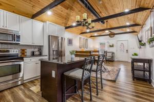 a kitchen with white cabinets and a bar with chairs at Cozy 3br downtown red door house in Jeffersonville