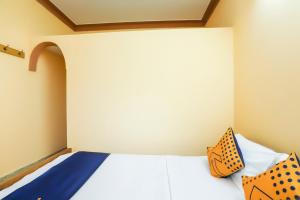 sypialnia z białym łóżkiem z pomarańczowymi i niebieskimi poduszkami w obiekcie OYO Renuka Lodge w mieście Belagula