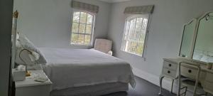 1 dormitorio con cama, tocador y espejo en Ardross House, en Amberley