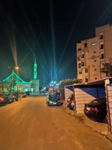 a parking lot with cars parked in front of a clock tower at Chalets and apartments Al-Nawras Village Ismailia in Ismailia