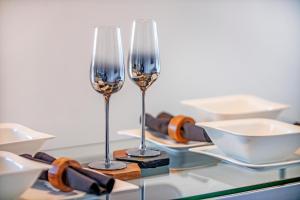 two wine glasses sitting on a glass table with plates at Mearns Street Suite ✪ Grampian Lettings Ltd in Aberdeen
