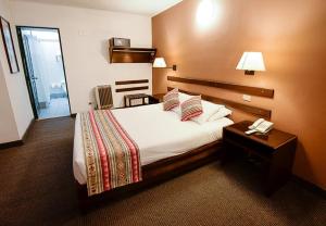 Habitación de hotel con cama y teléfono en Hotel Raymi, en Cusco