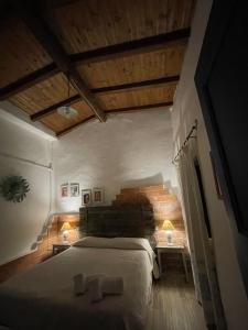 a bedroom with a large bed in a room with wooden ceilings at B&B Corte San Lussorio in Oliena