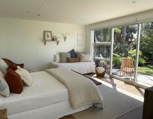 a bedroom with a bed and a couch and a window at Matarangi Beach Retreat in Matarangi