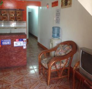 a room with a chair and a tv and a refrigerator at Hostal Brisas y Olas in San Juan del Sur