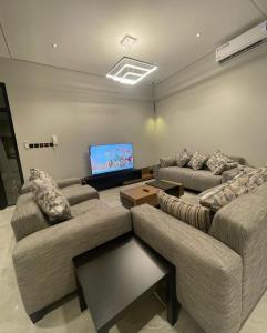 a living room with two couches and a flat screen tv at REST IN 2 in Unayzah