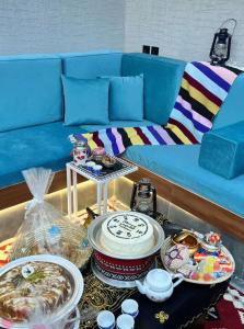 a living room with a blue couch with a table with dishes at REST IN 2 in Unayzah