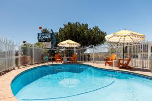 a swimming pool with two chairs and umbrellas at Quail Park Lodge in Kanab