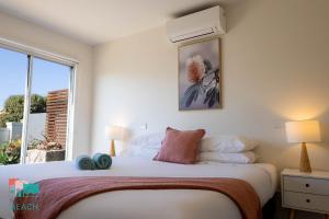 a white bedroom with a bed with a window at Botanic Beach in Warrnambool