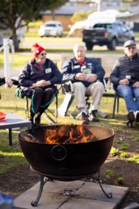 eine Gruppe von Menschen, die um eine Feuerstelle herum sitzen in der Unterkunft Reflections Forster Beach - Holiday Park in Forster