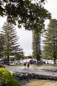 zwei Menschen, die auf einem Parkplatz die Straße entlang gehen in der Unterkunft Reflections Forster Beach - Holiday Park in Forster