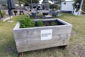 a wooden planter sitting in the grass with a sign in it at Reflections Forster Beach - Holiday Park in Forster