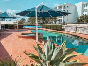 a large blue umbrella sitting next to a swimming pool at Ocean Front Apartment at the Bargara Blue Resort in Bargara
