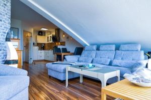 ein Wohnzimmer mit einem blauen Sofa und einem Tisch in der Unterkunft Haus Nordseebrandung NB74 in Cuxhaven