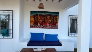 a living room with a blue couch and a painting on the wall at Nyumbani Tamu in Watamu