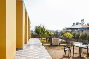 un patio con tavoli, sedie e ombrellone di SPOT ON Saini Guest House a Roorkee