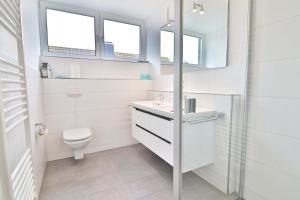 a white bathroom with a toilet and a sink at Orange Hygge Haus in Langeoog +17 photos