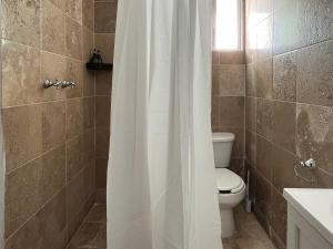 y baño con aseo y cortina de ducha. en La Casa del Agua Puebla en Acatepec