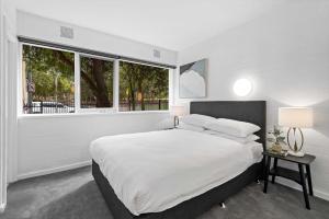 a white bedroom with a large bed and a window at Stunning 1-Bed Ground Floor Unit with Front Yard in Melbourne