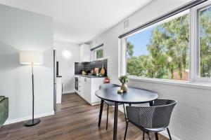 eine Küche mit einem Tisch und Stühlen sowie einem Fenster in der Unterkunft Modern 1-Bed Apartment with Cosy Balcony in Melbourne