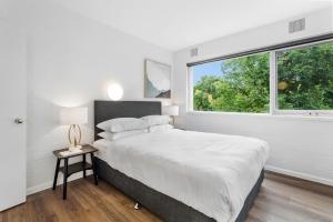 ein weißes Schlafzimmer mit einem großen Bett und einem Fenster in der Unterkunft Modern 1-Bed Apartment with Cosy Balcony in Melbourne