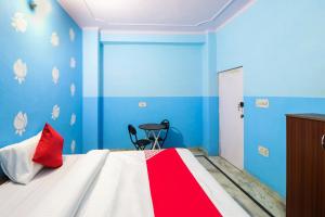 a bedroom with blue walls and a bed with a red pillow at OYO Hotel Moon Tara in Faridabad