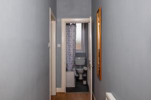 a hallway to a bathroom with a toilet and a mirror at Cozy 2 Bedroom Apartment by Leith Water/ Ocean in Edinburgh