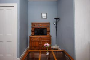 a living room with a television and a vase of flowers at Cozy 2 Bedroom Apartment by Leith Water/ Ocean in Edinburgh