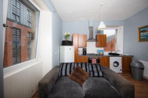 a living room with a couch and a kitchen at Cozy 2 Bedroom Apartment by Leith Water/ Ocean in Edinburgh