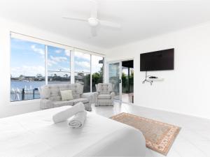 a white bedroom with a large bed and a tv at 21 Melaleuca Drive -LJHooker Yamba in Yamba