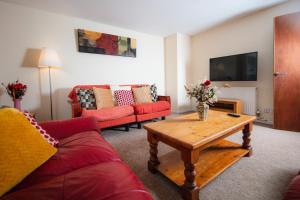 a living room with red couches and a coffee table at Fab Arthur Seat Views, Old Town Apartment in Edinburgh
