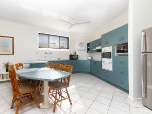 a kitchen with blue cabinets and a table and chairs at 21 Melaleuca Drive -LJHooker Yamba in Yamba