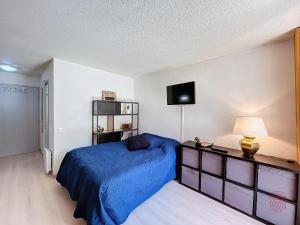 Schlafzimmer mit einem blauen Bett und einem TV in der Unterkunft Studio Lamalou-les-Bains, 1 pièce, 2 personnes - FR-1-451-207 in Lamalou-les-Bains