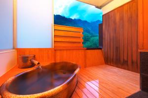 a bath tub in a room with a large window at Hotel Hotaka in Takayama