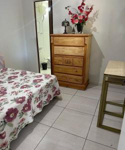 a bedroom with a dresser with a bed and a vase of flowers at Chácara R e A eventos in Uberlândia