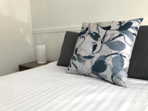a bed with a blue and white pillow on it at Orford Blue Waters Hotel in Orford