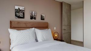 een slaapkamer met een wit bed en drie foto's aan de muur bij Your Central Base near Unicentro in Bogota