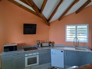 a kitchen with orange walls and a sink and a microwave at Villa titwoine in Pointe-Noire