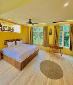 a bedroom with a bed and a table and windows at BAMBOO OASIS in Ubud