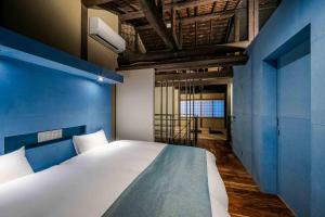 um quarto com uma cama grande e uma parede azul em Asagi an Machiya House em Quioto