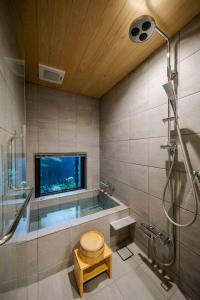 uma casa de banho com banheira e uma televisão na parede em Asagi an Machiya House em Quioto