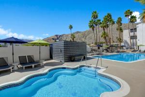 a pool at a hotel with palm trees and a mountain at The Dunes Hotel (Palm Springs) in Palm Springs