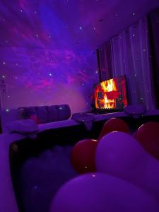 ein lila Zimmer mit Sofa und Kamin in der Unterkunft Deluxe appartement Jacuzzi in Freneuse
