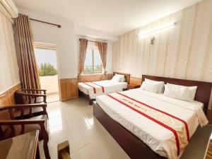 a hotel room with two beds and a window at Ngọc Hân Hotel By The Moment in Vung Tau