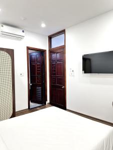 a room with two doors and a tv on the wall at Han Riverine Hotel & Cafeteria DaNang in Danang