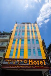 ein hohes gelbes Gebäude mit einem Hotelschild drauf in der Unterkunft Khách sạn Phước Lộc Thọ 2 - 福禄寿 in Ho-Chi-Minh-Stadt