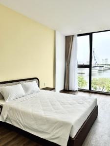 a bedroom with a large bed with a large window at Han Riverine Hotel & Cafeteria DaNang in Da Nang