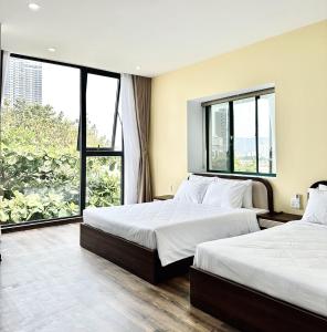 two beds in a hotel room with large windows at Han Riverine Hotel & Cafeteria DaNang in Danang +28 photos
